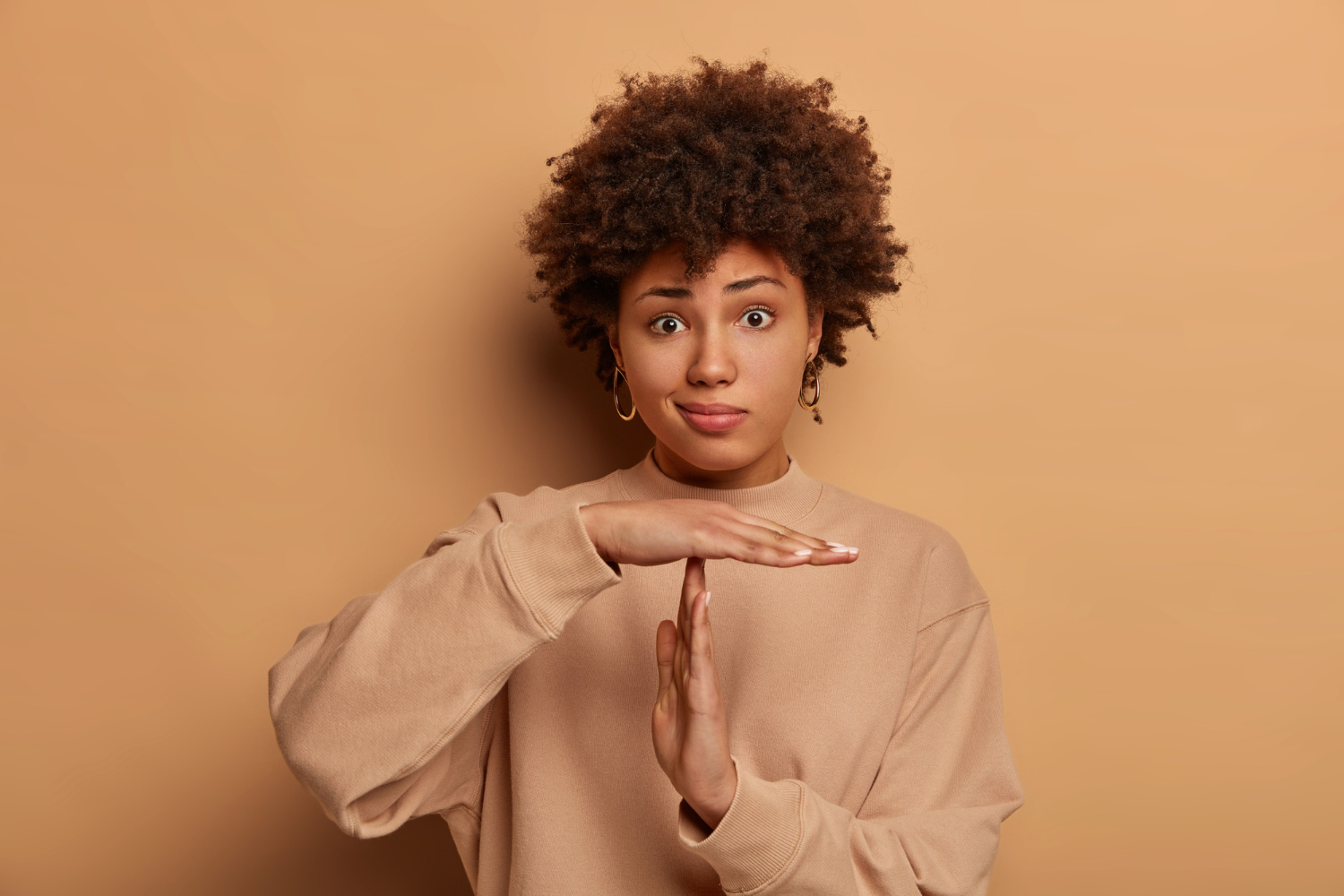 photo-puzzled-dark-skinned-woma-makes-time-out-gesture-has-serious-frustrated-expression-curly-hairstyle-dressed-casual-sweatshirt-poses-against-beige-wall-needs-stop